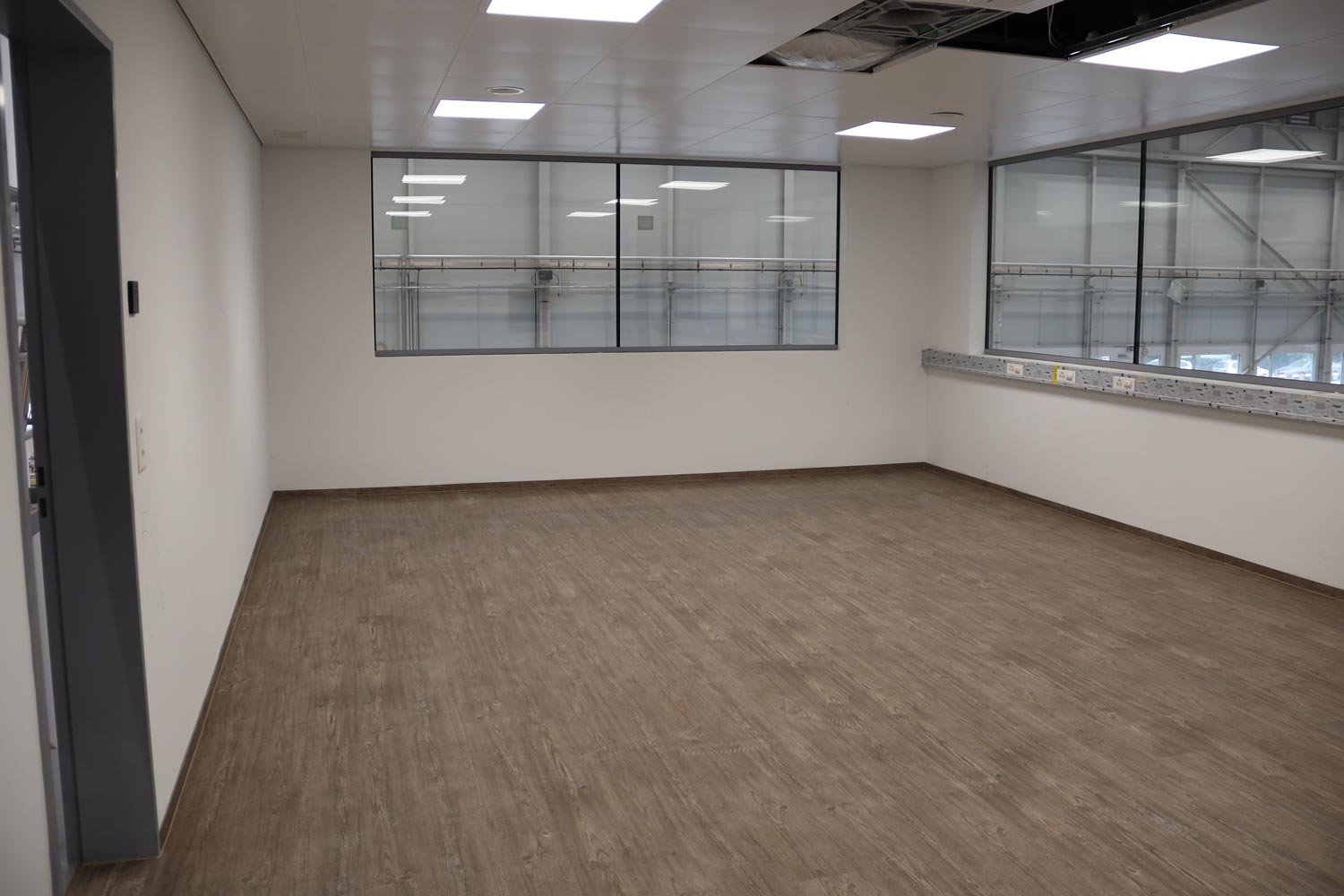 Sitzungszimmer mit brauen Parkettboden und weissen Wänden.
